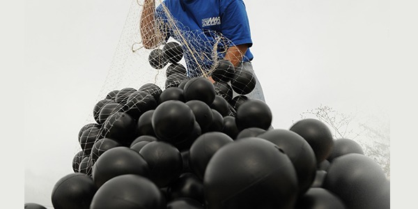 Armor Ball AQUA 275 water-filled wind-resistant floating covers on a large open frac pond, engineered to withstand wind speeds up to 75 MPH
