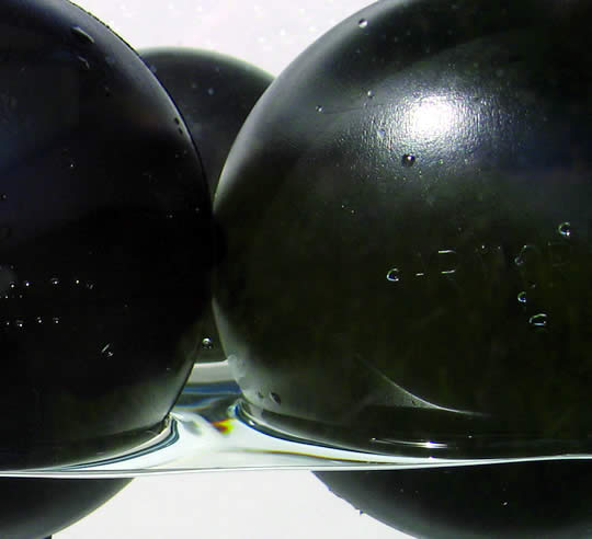 Armor Ball modular hollow-plastic floating ball covers deployed on an industrial water storage pond for evaporation and algae control