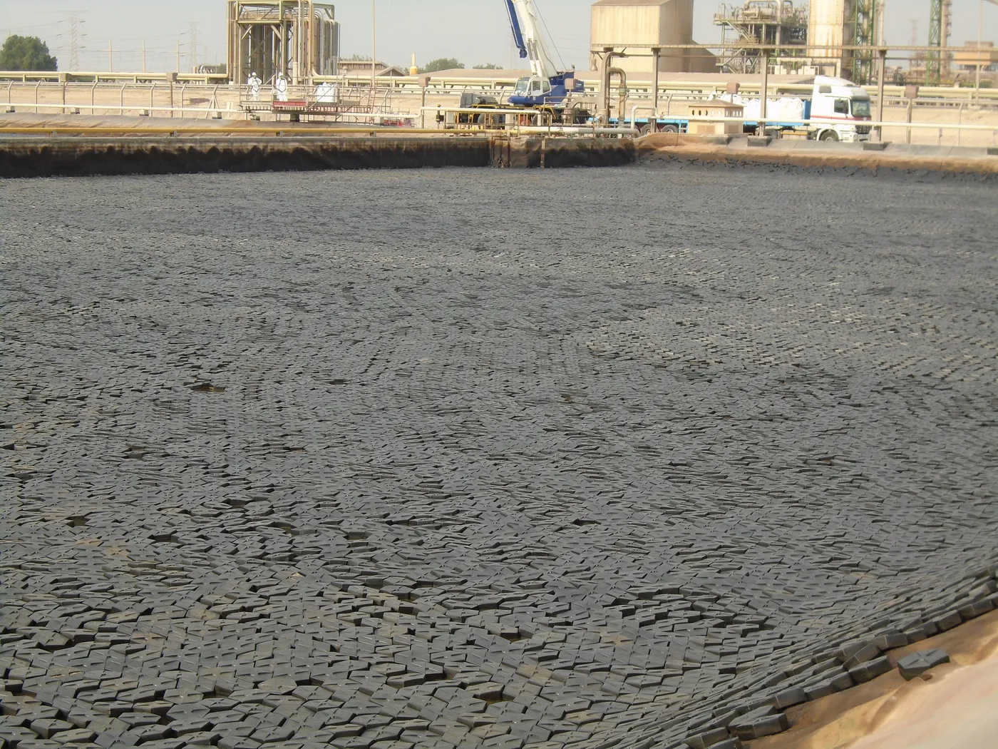 Hexprotect AQUA hexagonal floating cover tiles fully blanketing an industrial treatment pond