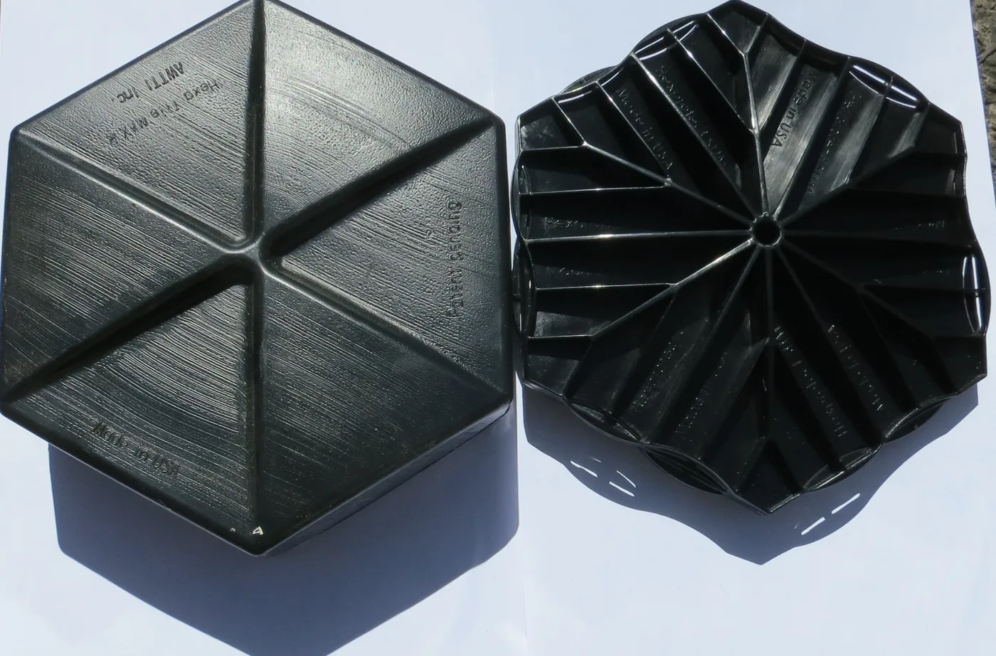 Studio product photo of two black Hexprotect AQUA hexagonal floating cover tiles