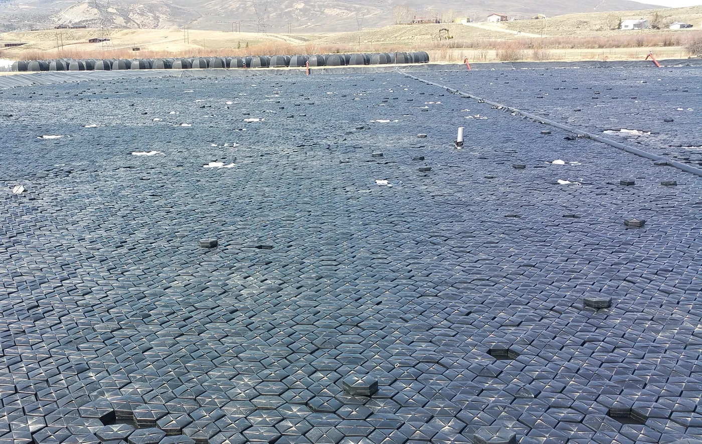 Hexprotect MAX R insulated floating cover tiles blanketing an industrial lagoon in winter