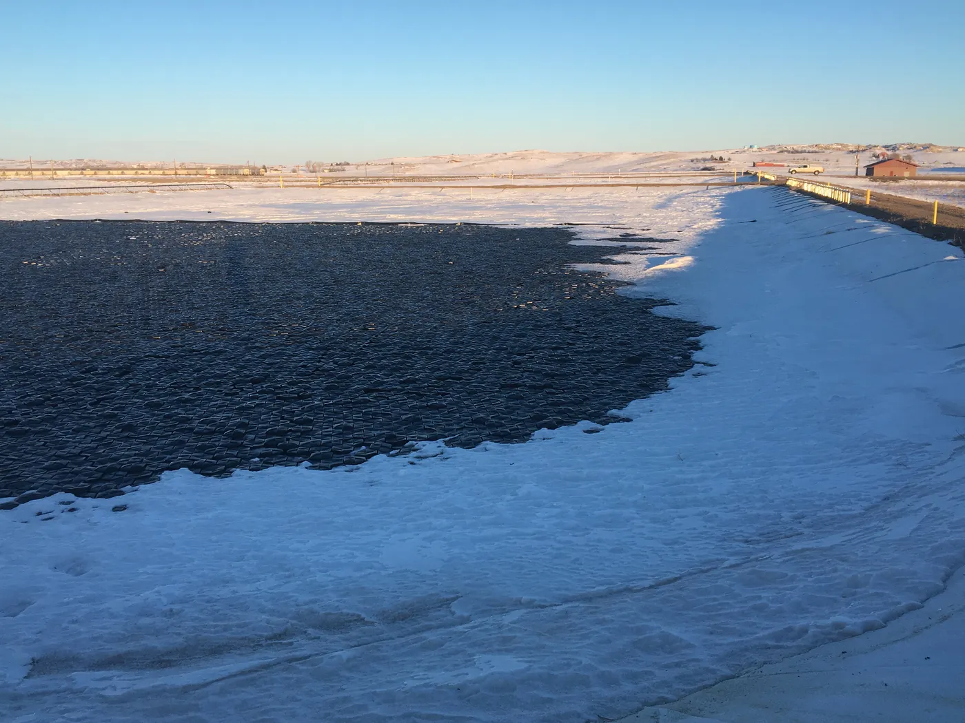 Hexprotect MAX R insulated cover holding back snow and ice on a partially frozen pond